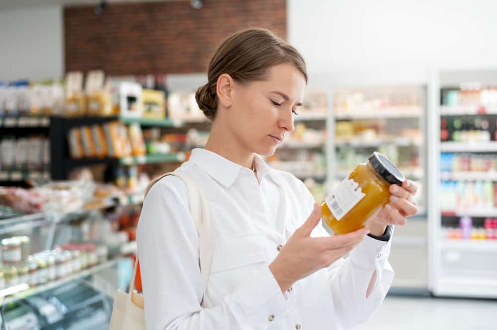 a woman is looking at a jar of honey in a grocery store .