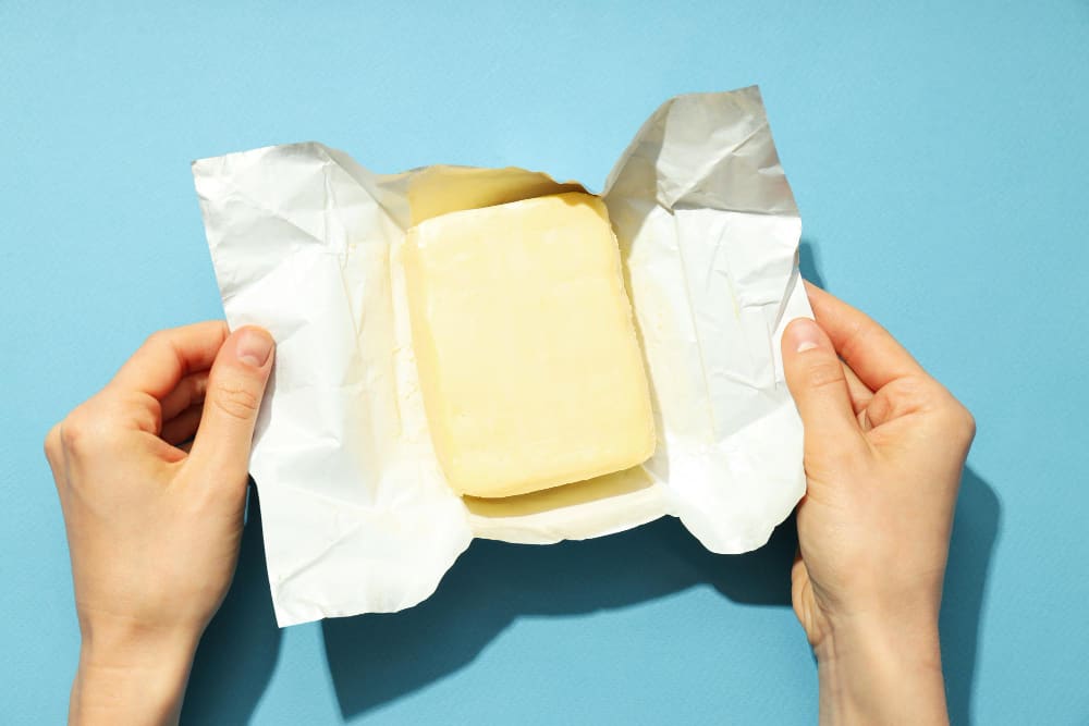 a person is holding a piece of butter in their hands .