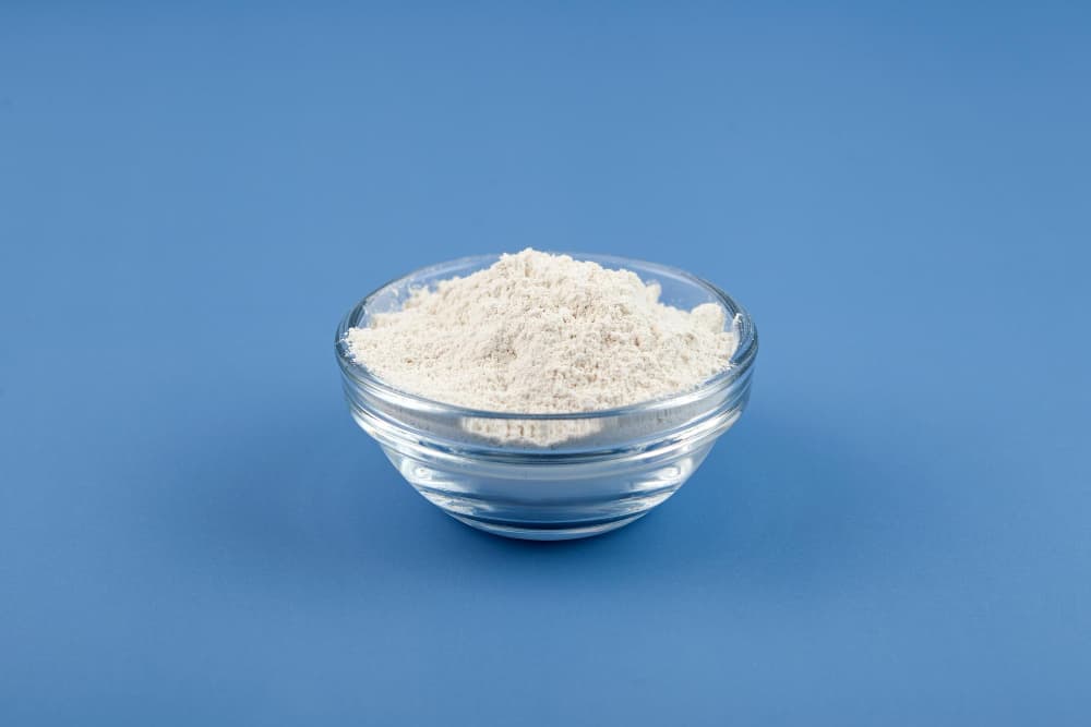 a glass bowl filled with white powder on a blue surface .