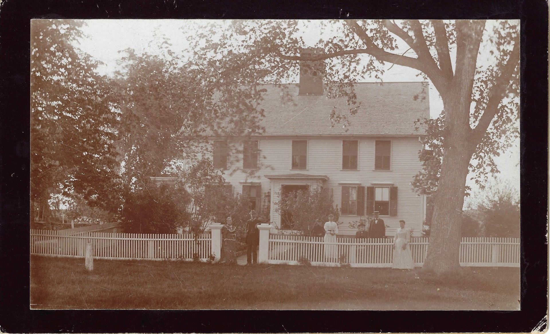 A black and white photo of a house with a fence