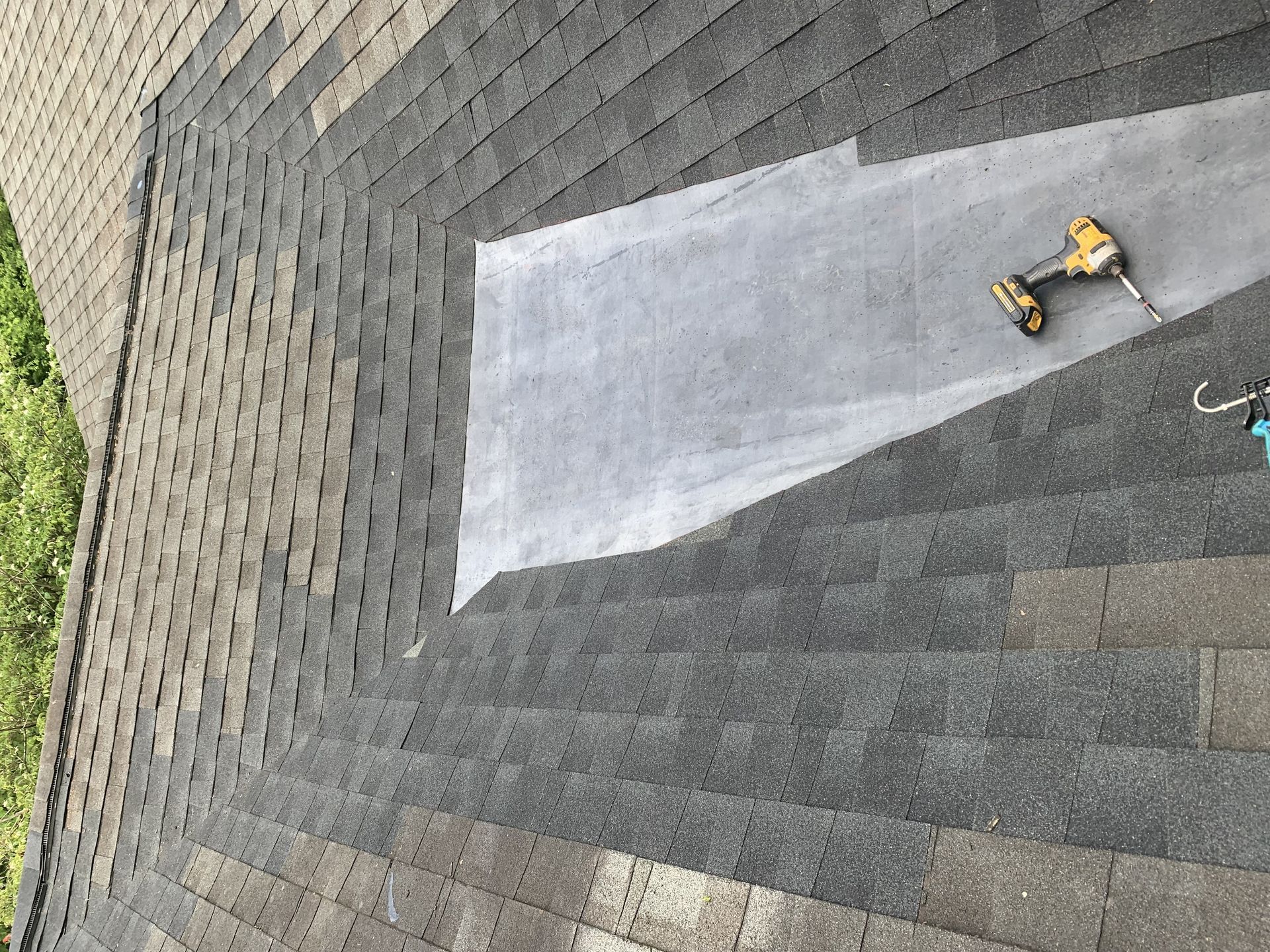 A drill is sitting on top of a roof next to a piece of plastic.