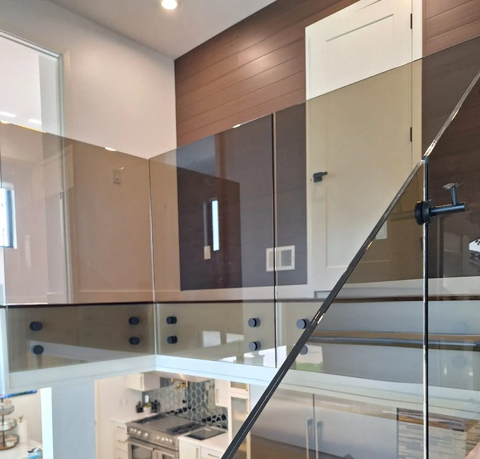 Interior view: glass railing, modern architecture, kitchen visible below, natural light, bronze glass.