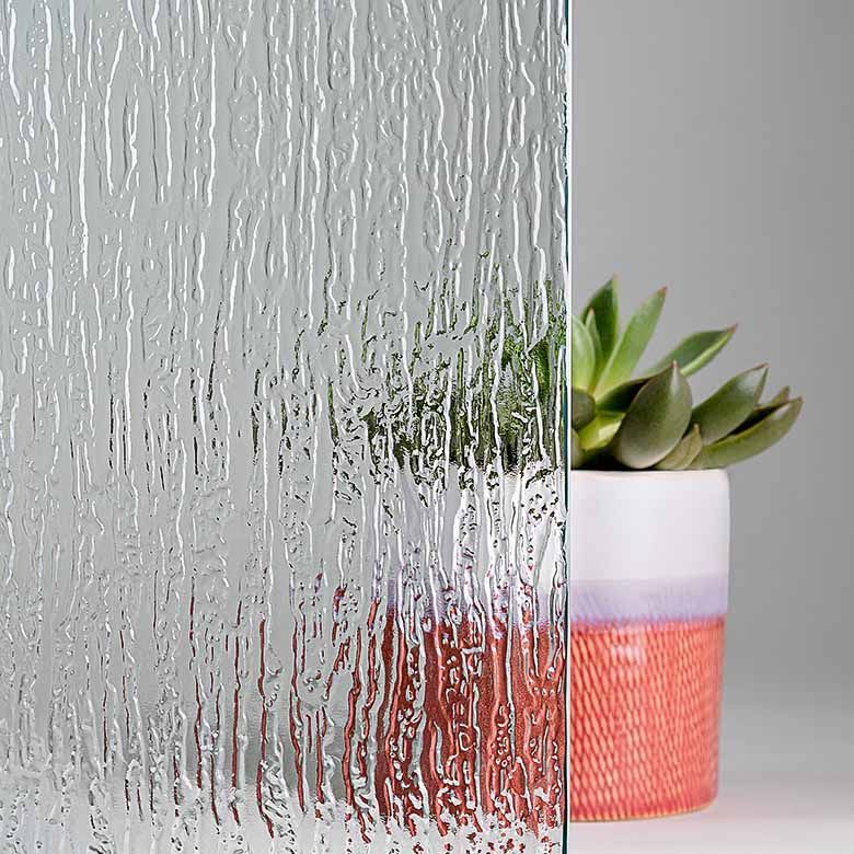 Textured glass pane with vertical striations, next to a potted succulent plant.