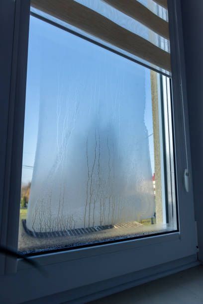 Window with condensation and blue sky visible outside.