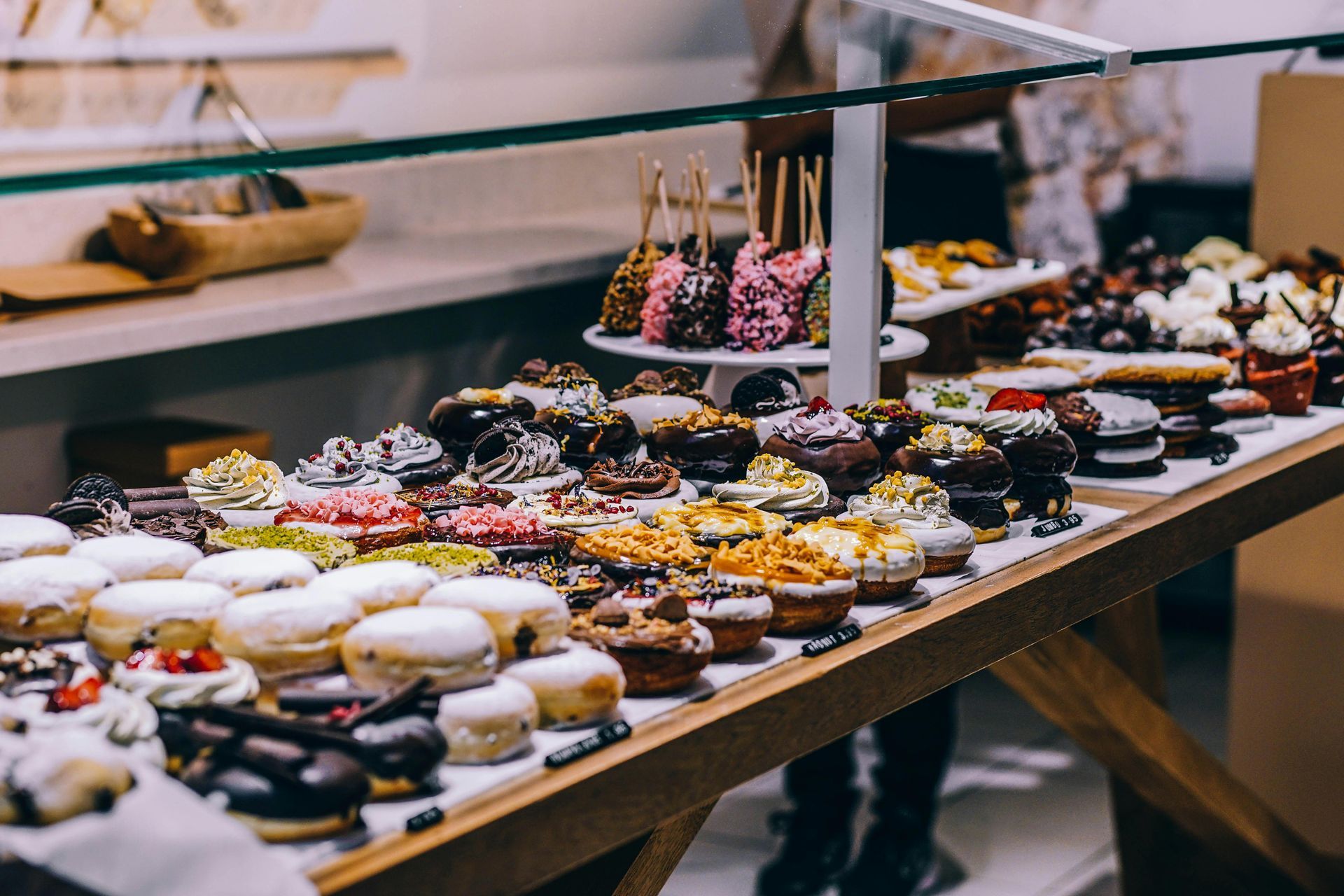 Glass display case filled with various decorated desserts, including cupcakes and doughnuts.