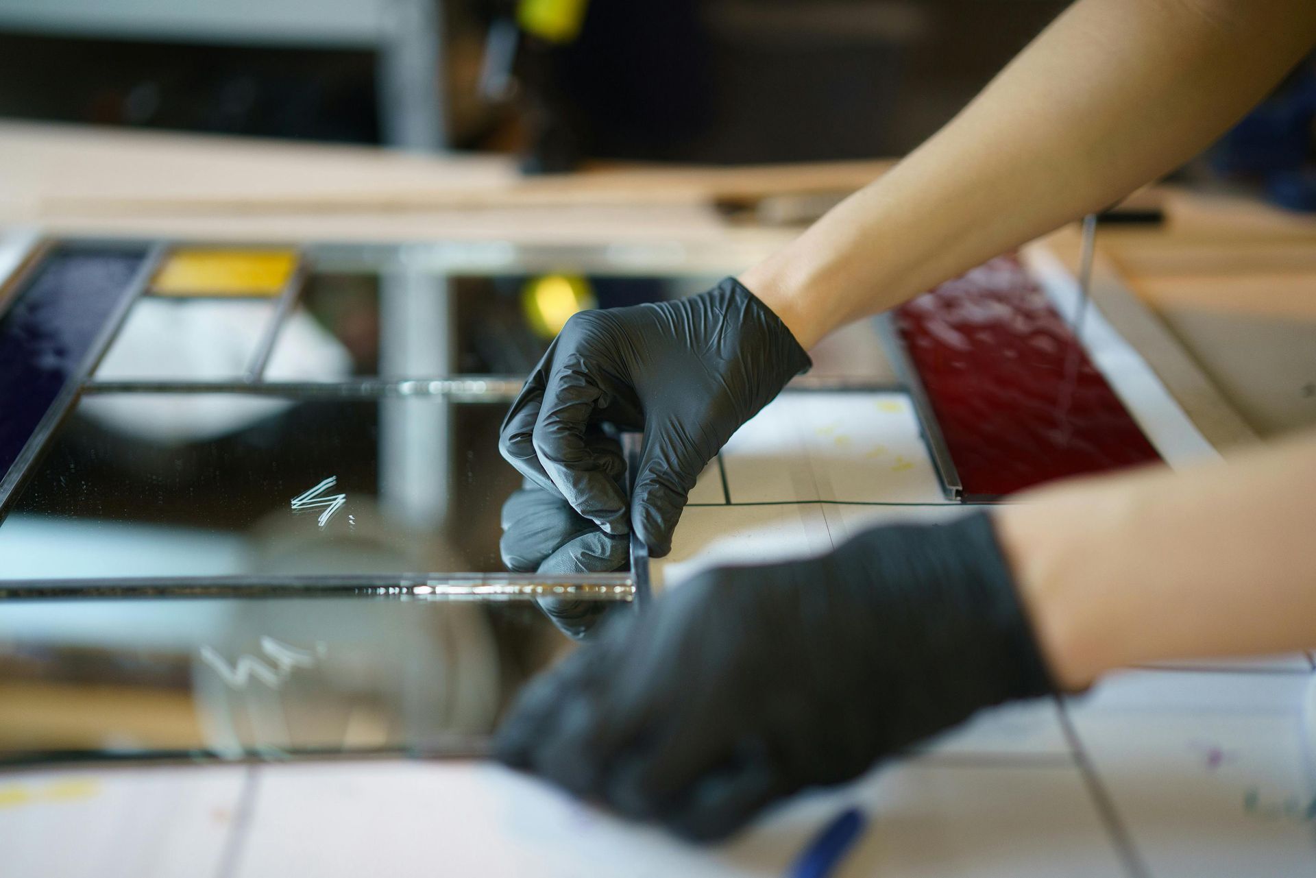 Hands in black gloves assembling stained glass.