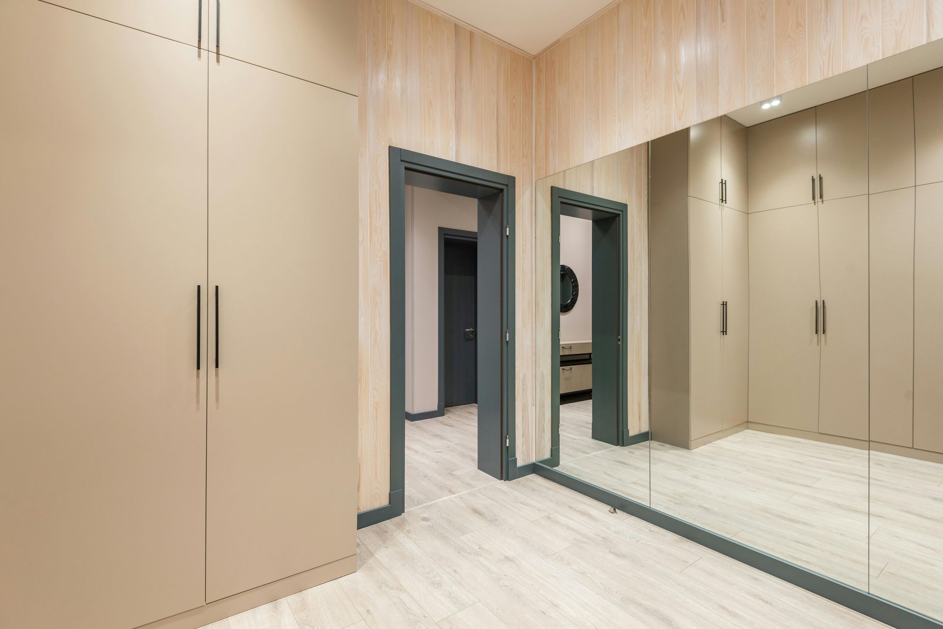 Walk-in closet with beige cabinets, full-length mirror, and gray door frames.