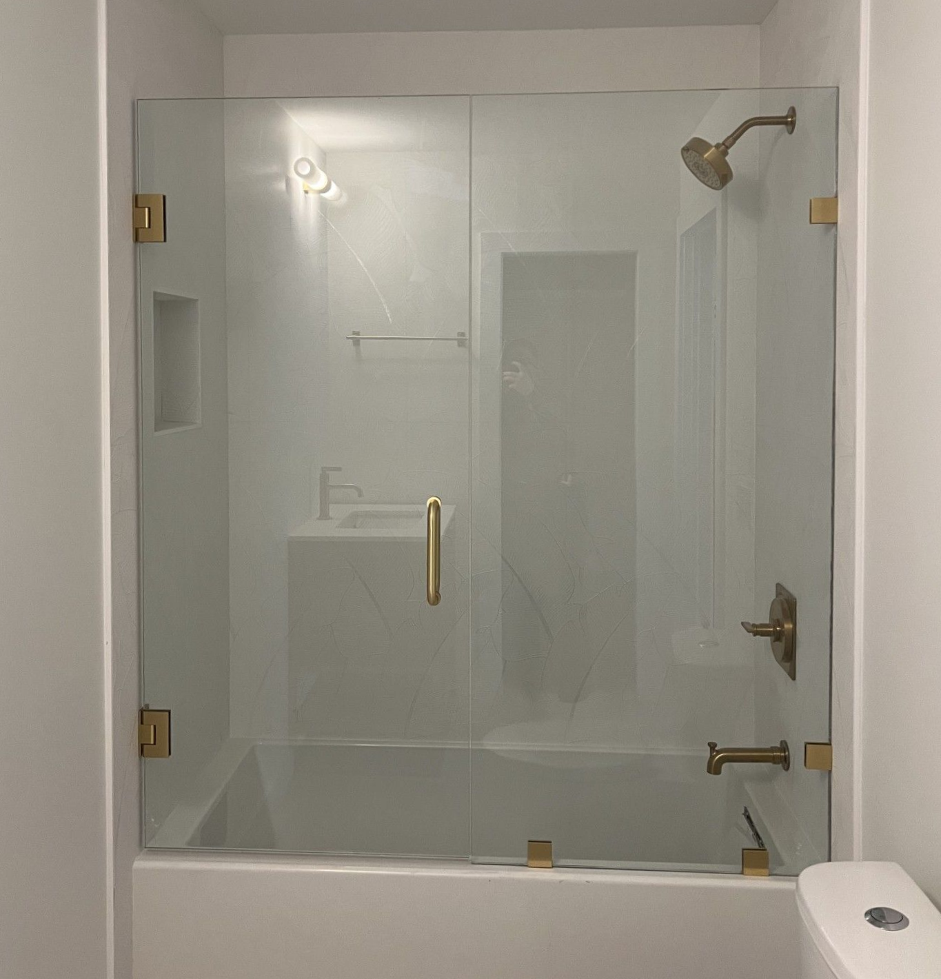 Bathroom with glass shower doors and gold fixtures.