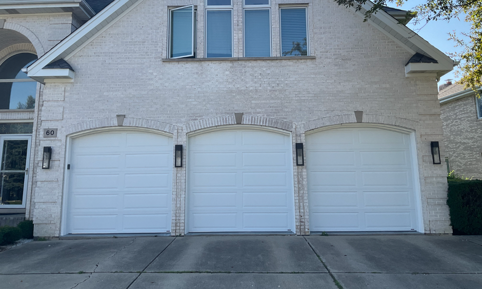 White brick house with three white garage doors and a concrete driveway