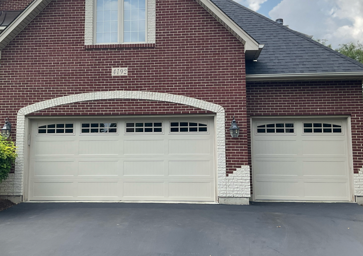 Brick house with two white garage doors and a dark driveway