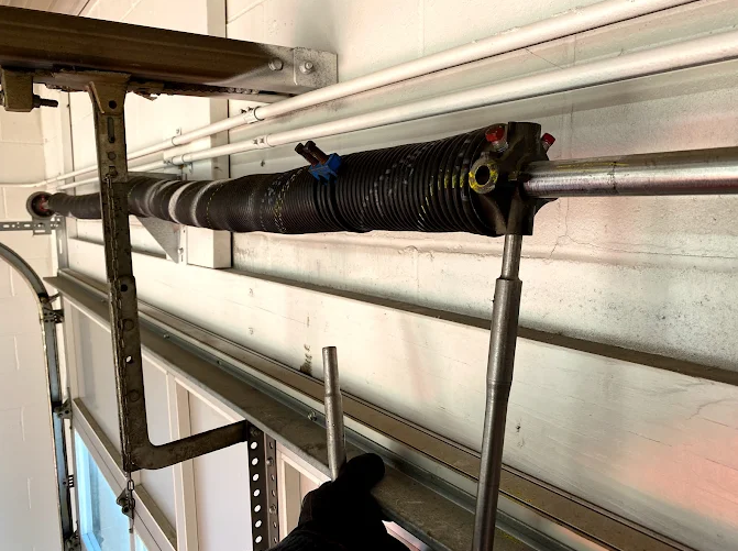 Black insulated pipe along a wall, supported by metal braces in a utility space