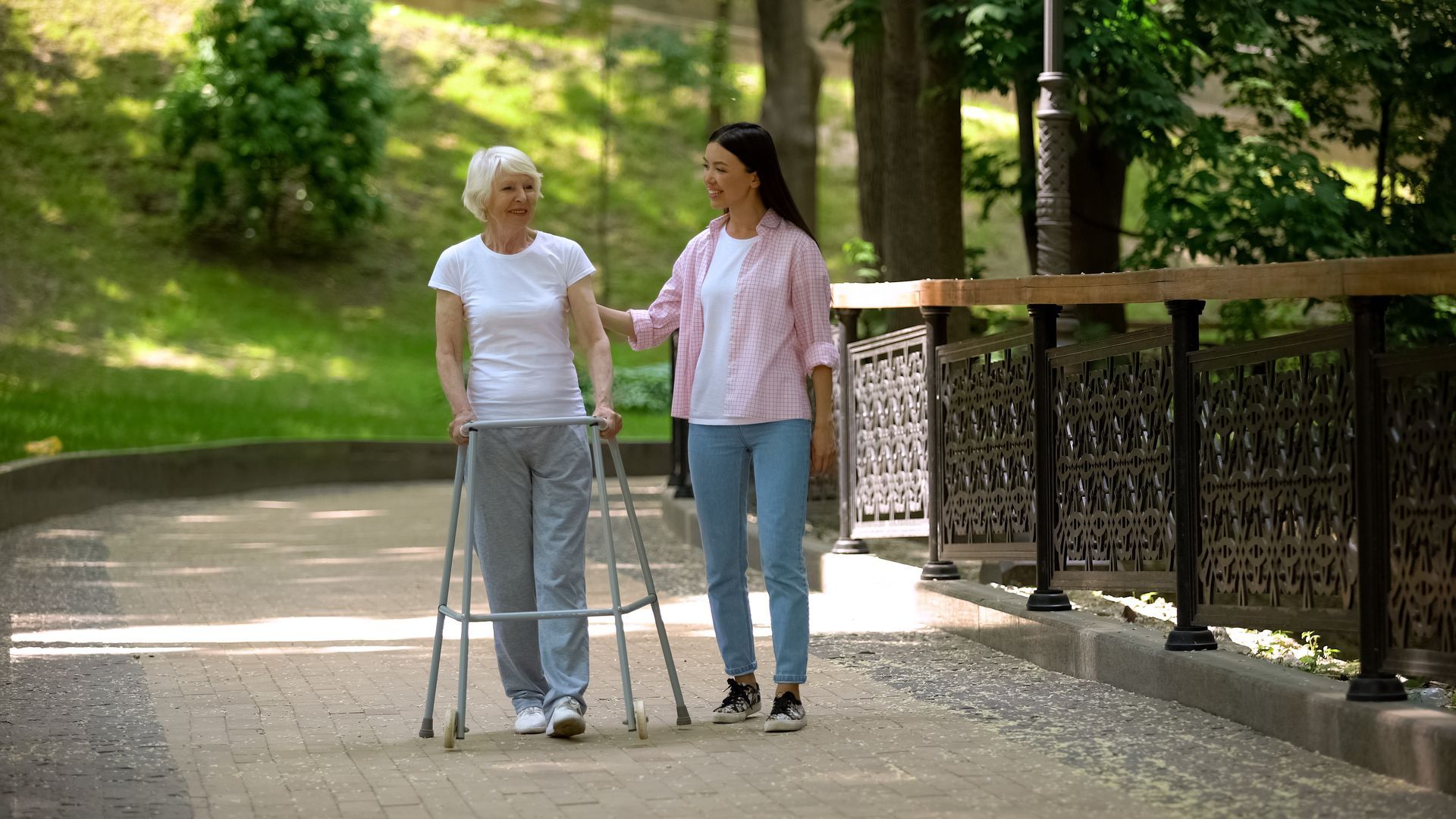 A woman is helping an elderly woman with a walker.