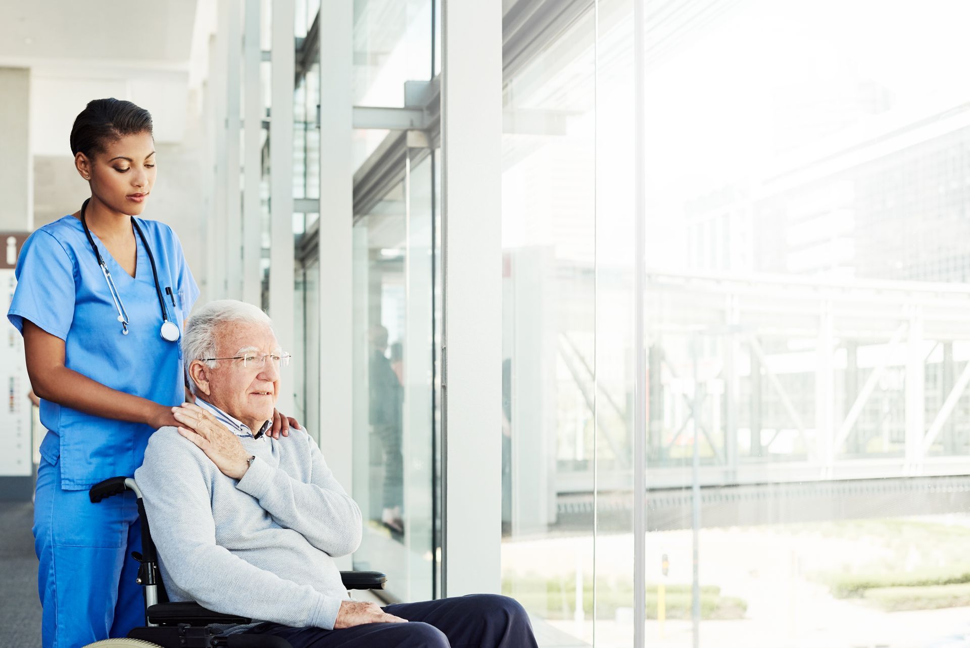 A nurse is helping an elderly man in a wheelchair.