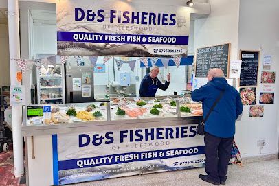 A customer stands at the D&S Fisheries counter, where an employee displays fresh seafood for sale in an indoor market.
