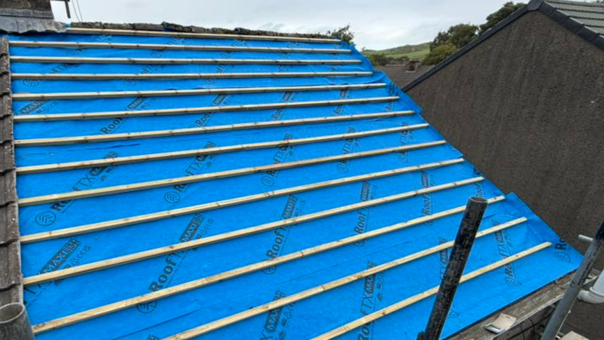 Dark grey resin driveway leading to a white garage door, flanked by gardens with greenery.