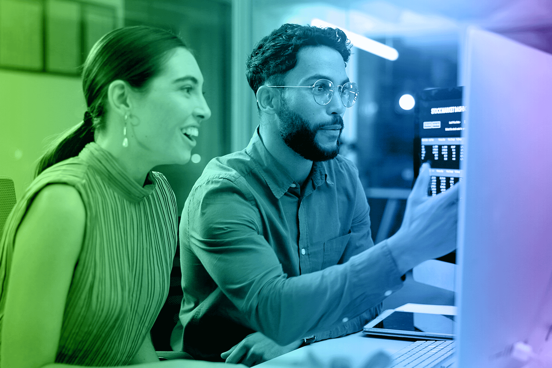 Man and woman looking at computer screen, man pointing, green to purple gradient.