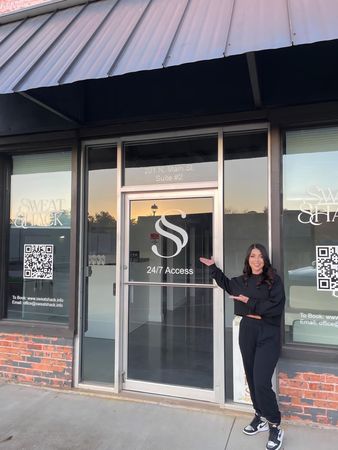 A woman is standing in front of a building with the letter s on the door