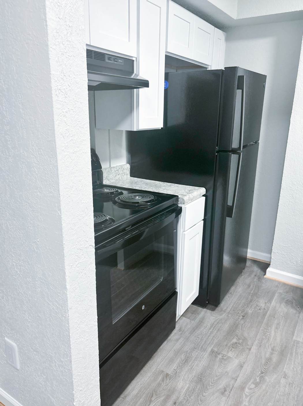 A kitchen with a black refrigerator , black stove , and white cabinets.