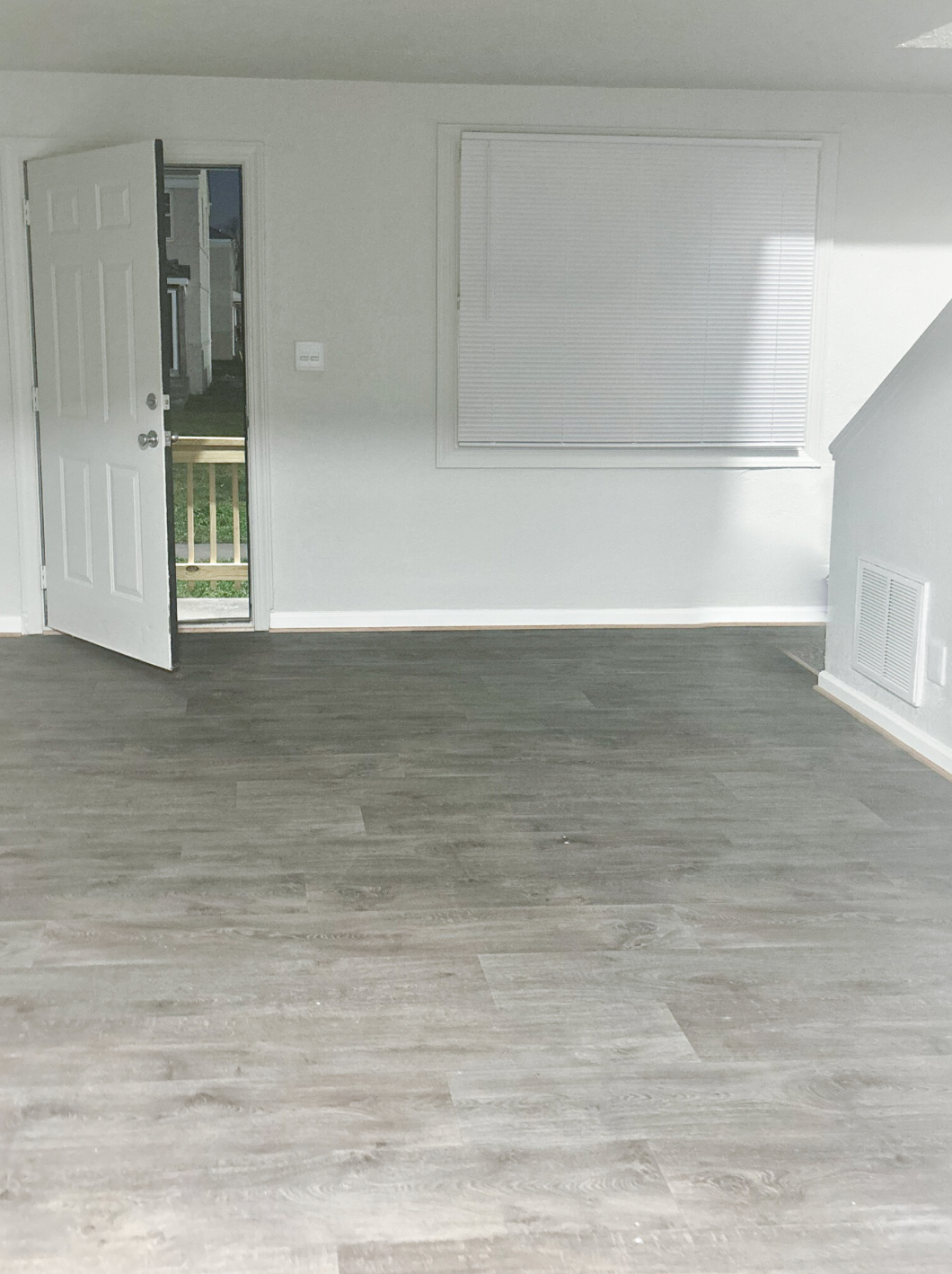 An empty room with a wooden floor and a door.