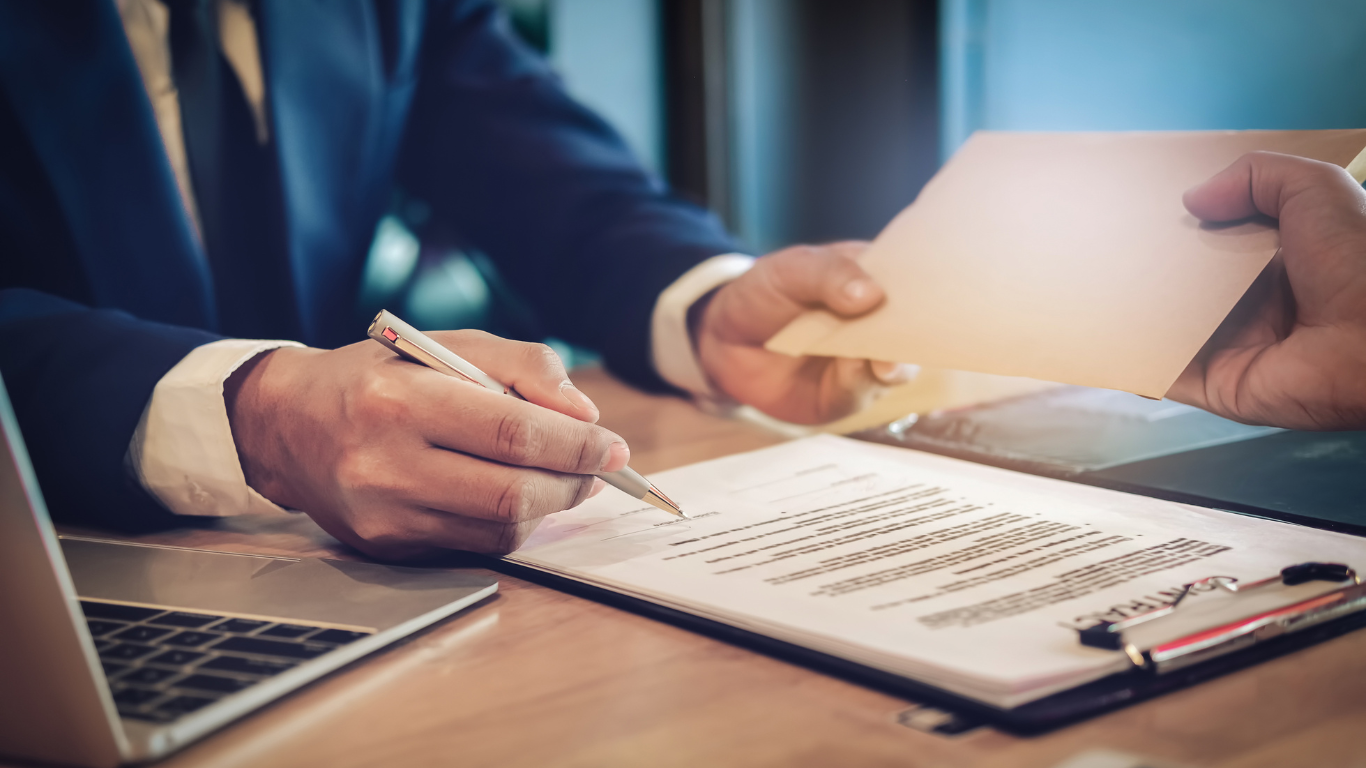 a man in a suit is signing a document while another man holds a piece of paper .