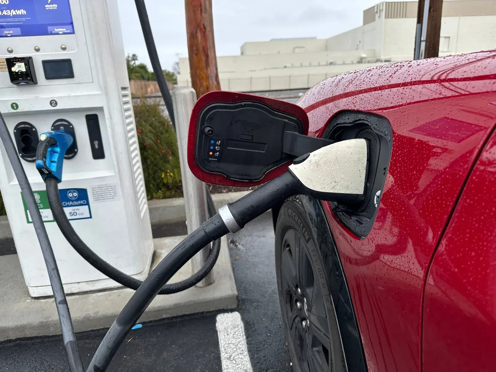 A red electric car is being charged at a charging station.