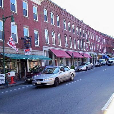 A car is driving down a street in front of a brick building