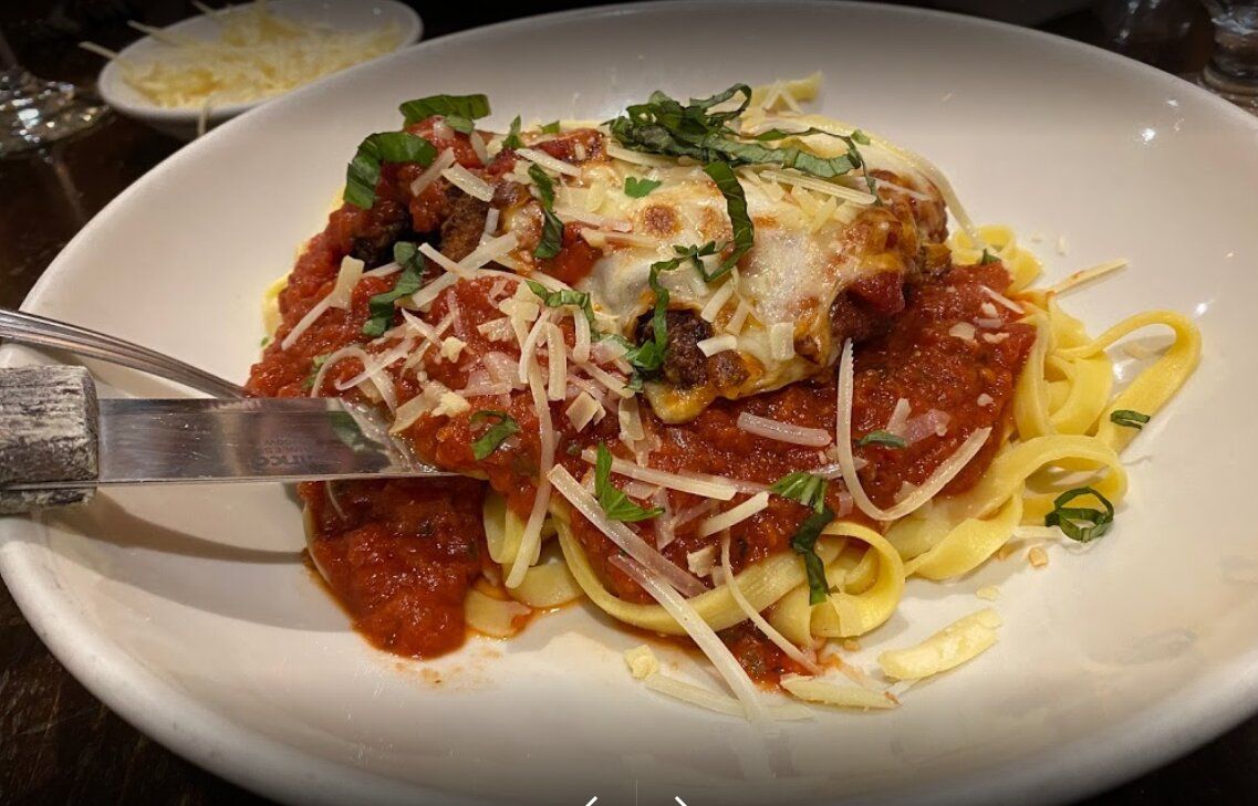 A close up of a plate of pasta with meatballs and sauce on a table.