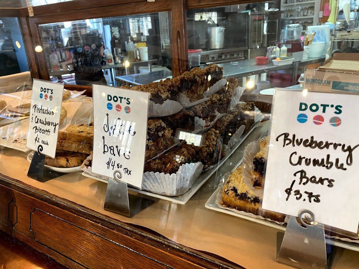 A display case filled with a variety of desserts including blueberry crumble bars.