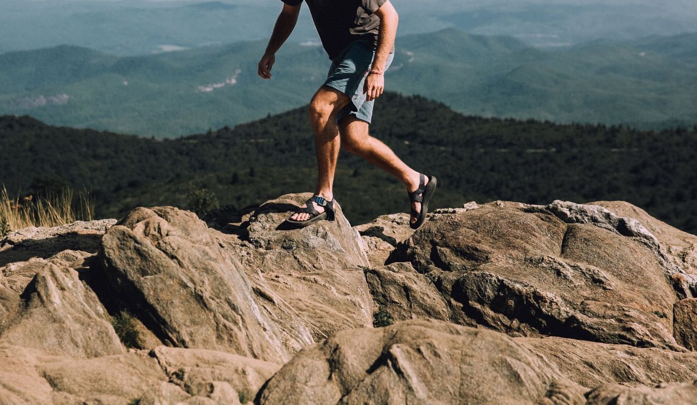 A man is jumping over rocks on top of a mountain.