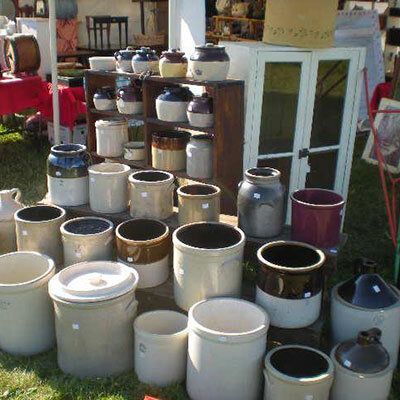 A bunch of pots and jars are sitting on a table in the grass.