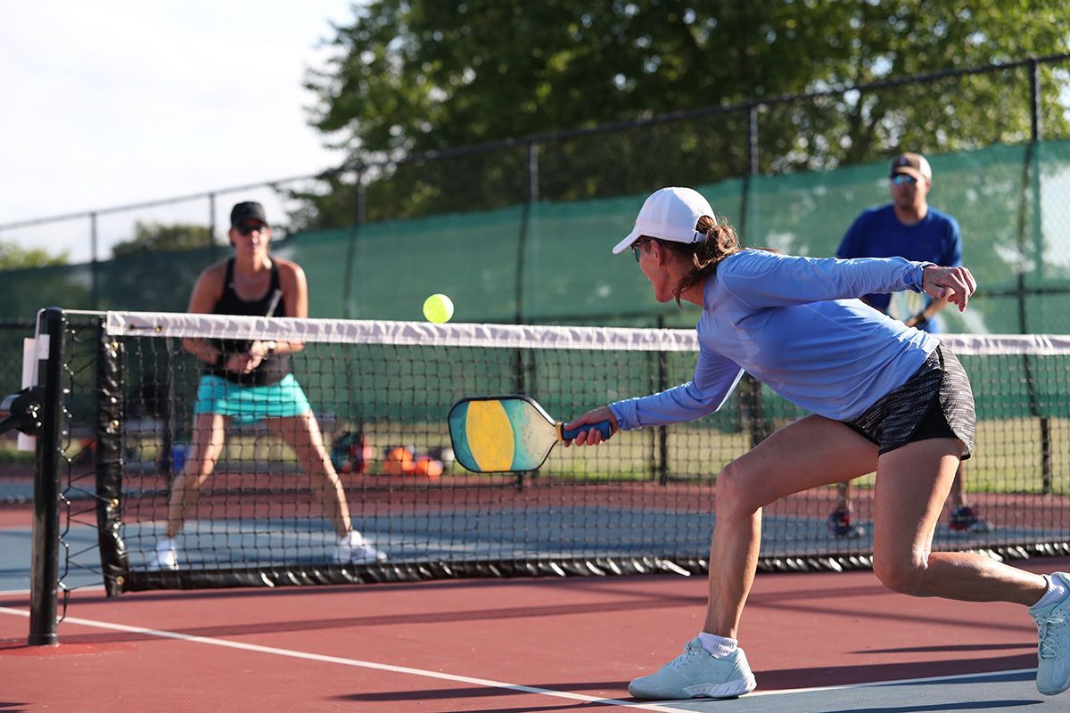 Two women are playing a game of pickleball on a tennis court.