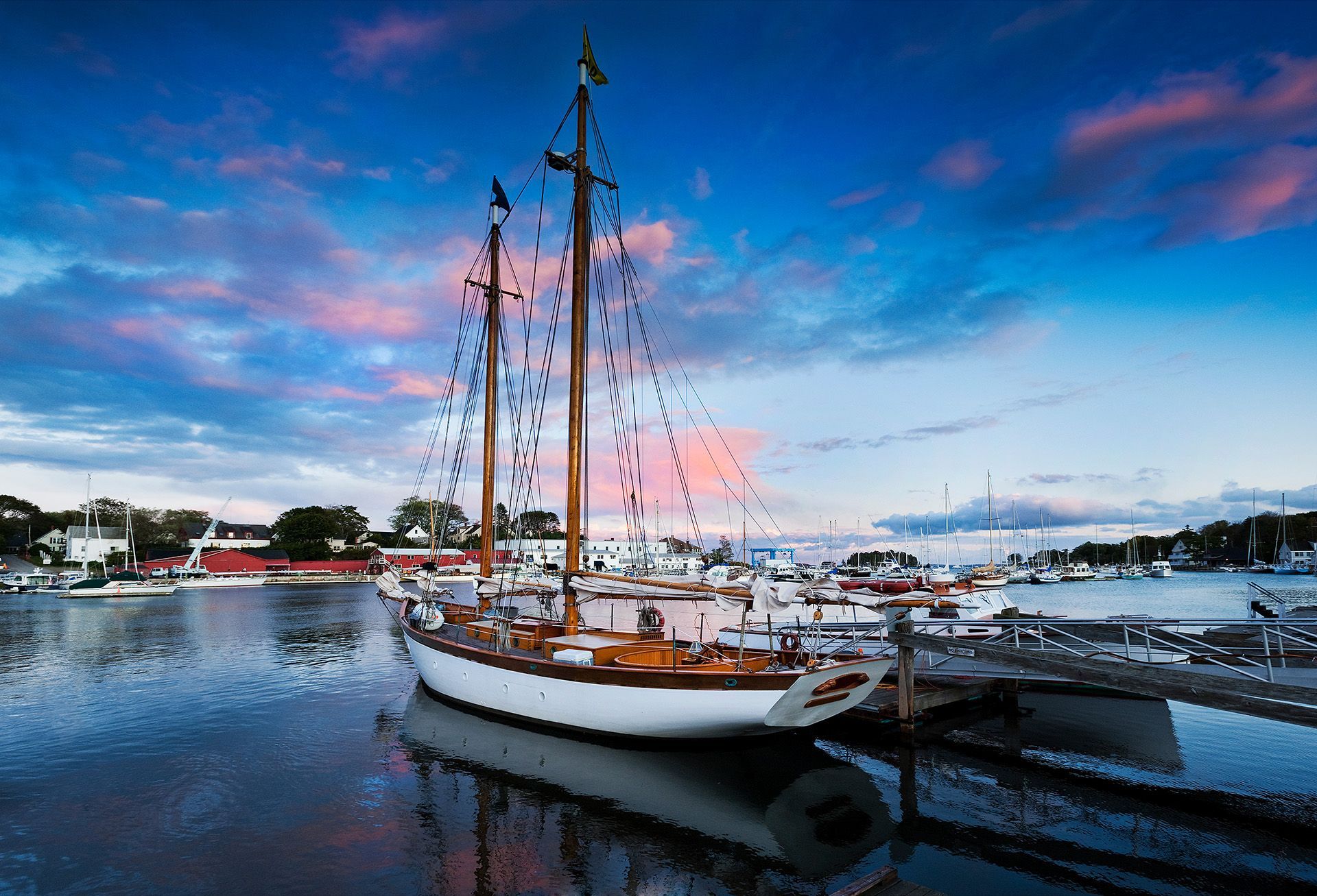 A sailboat is docked in a harbor at sunset