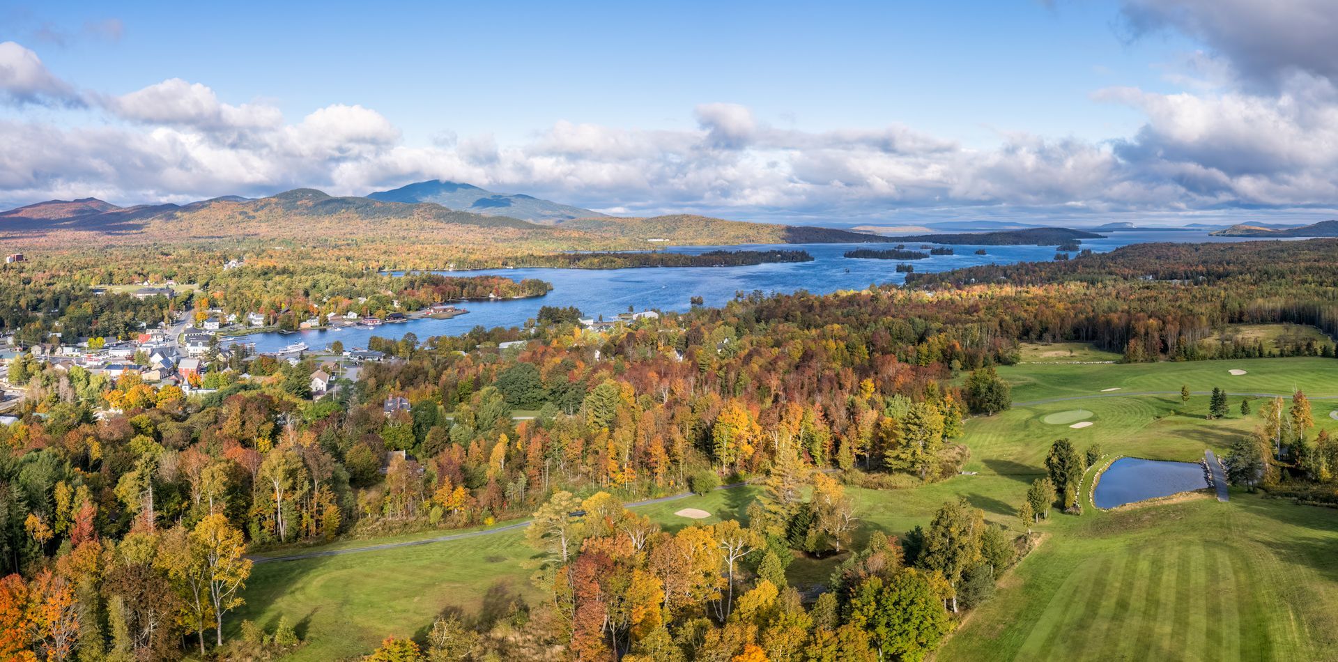 An aerial view of a golf course surrounded by trees and a lake.