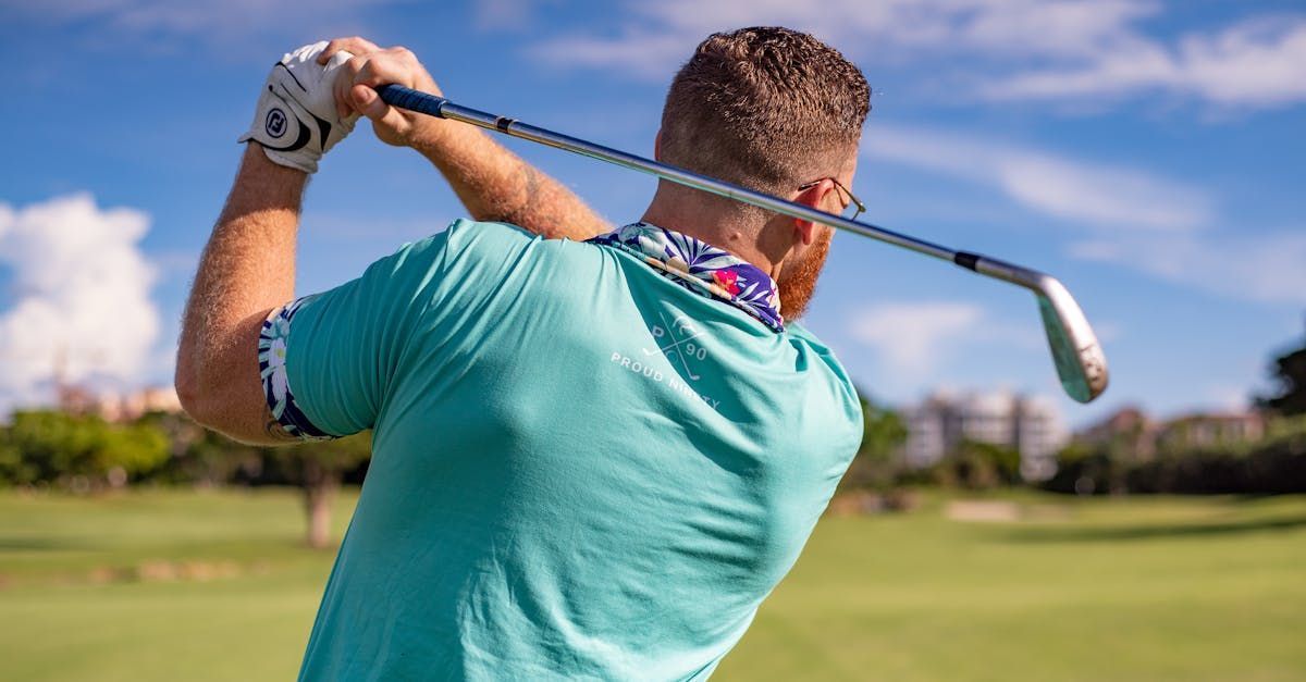 A man is swinging a golf club on a golf course.