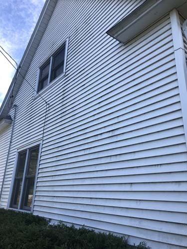 two story white home with mold and mildew on the side prior to washing