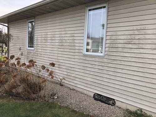 Single story taupe home with dirty, mold and mildew across entire siding
