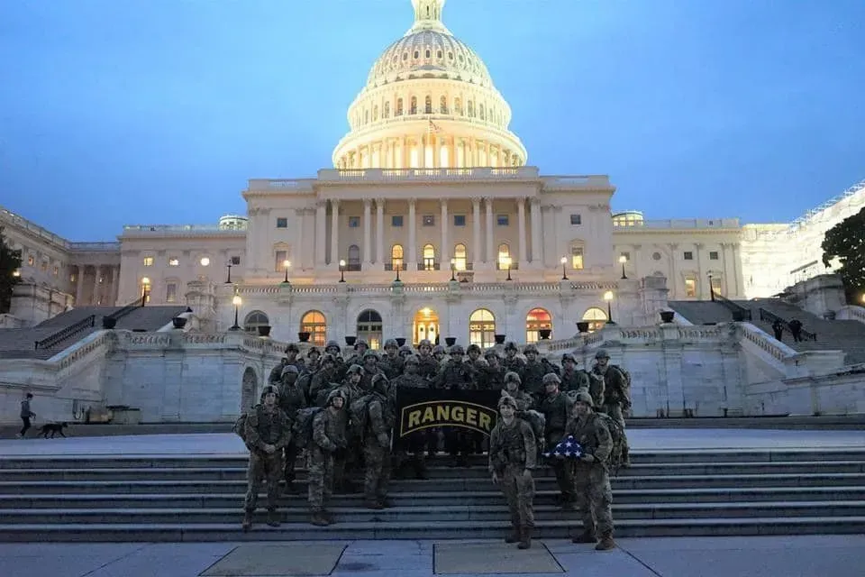Rangers holding a banner and flags, stand on Capitol steps at dusk. U.S. Capitol building in background.