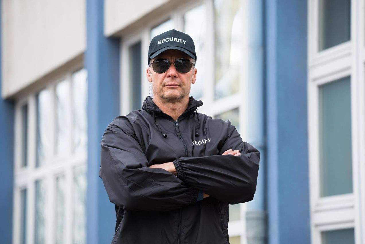 Security guard wearing sunglasses and a hat with 