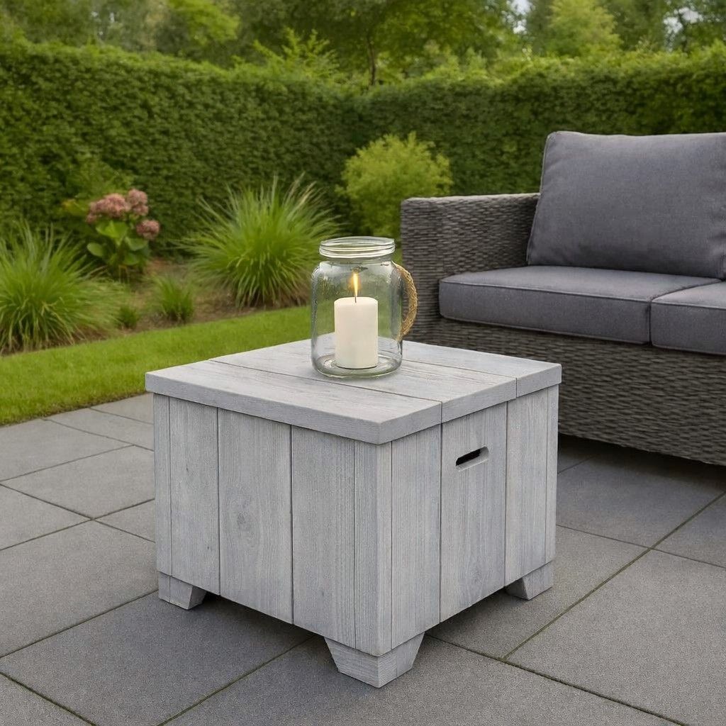 Witte houten terrastafel met kaarsenhouder naast een grijze buitenbank op een tuinterras