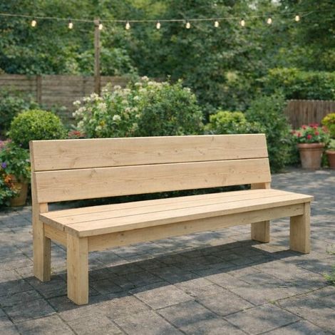 Een lichte houten bank op een stenen terras met tuingroen en lichtslingers op de achtergrond.