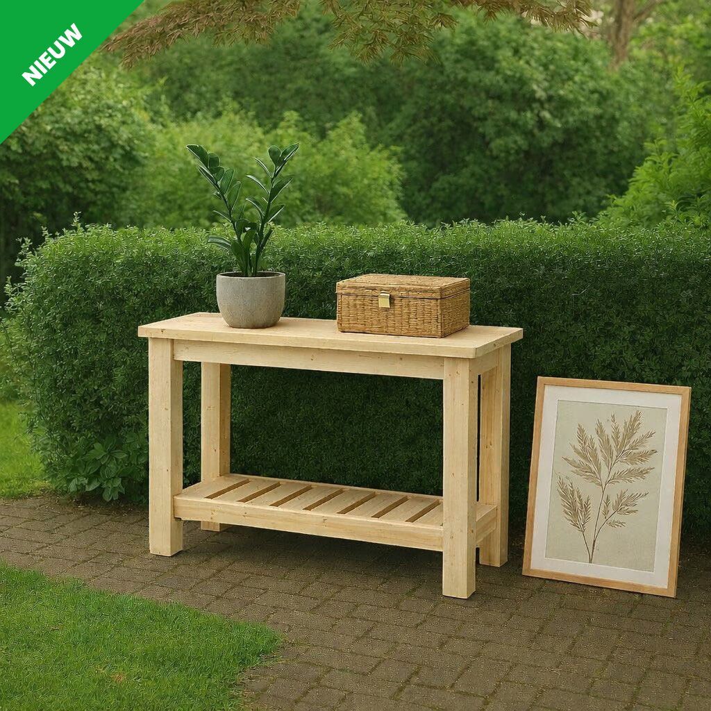Houten tafel met potplant, rieten mand en ingelijste botanische prent op gras met een heg op de achtergrond.