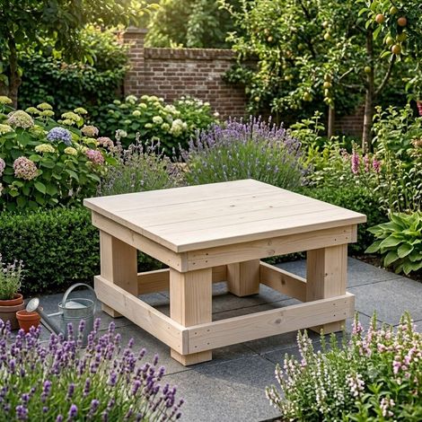 Houten terrastafel in een weelderige tuin, omgeven door bloeiende bloemen en groen.
