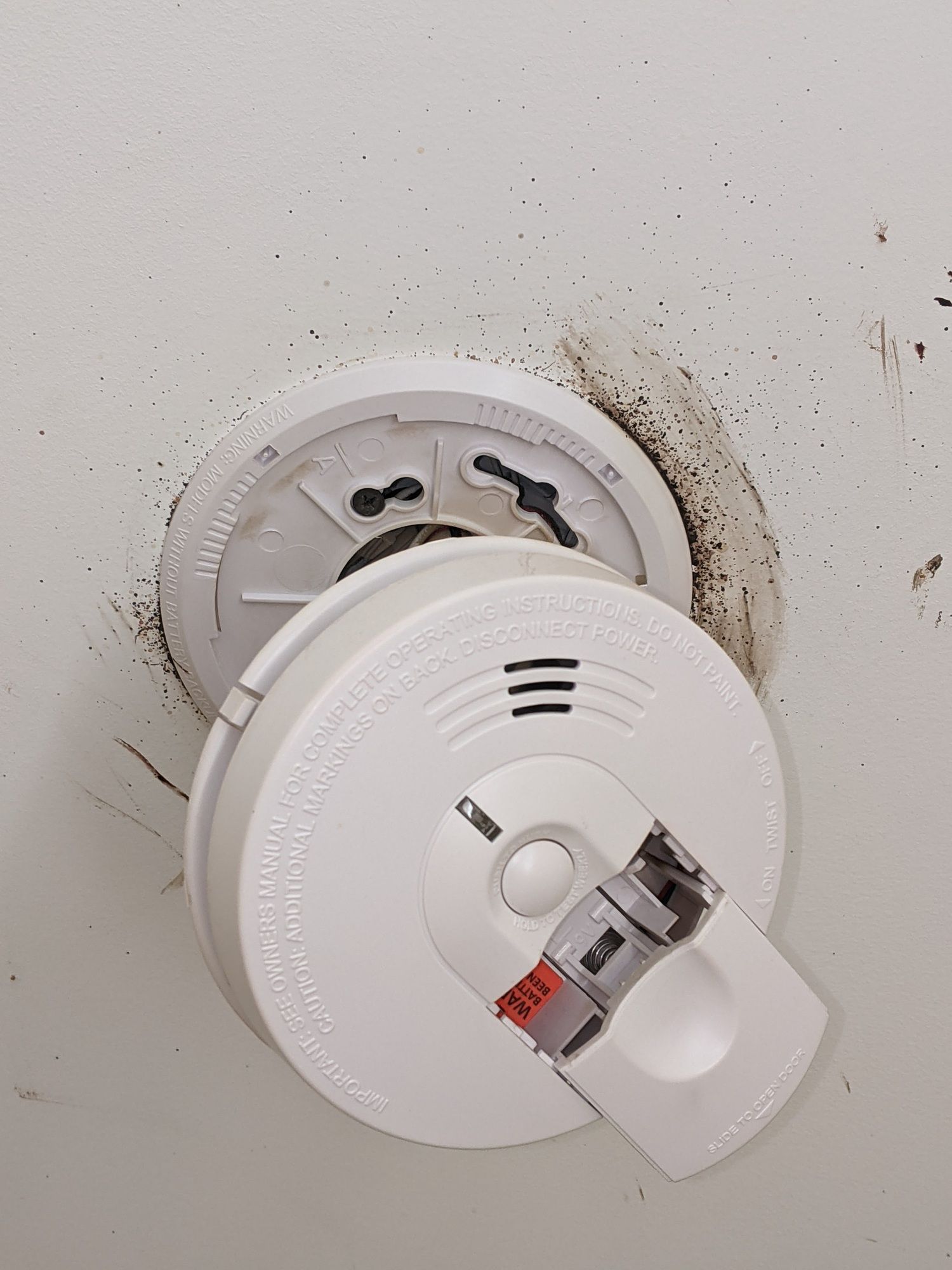 A smoke detector is being removed from the ceiling.