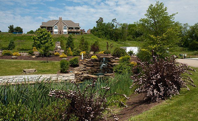 A large house is sitting on top of a hill surrounded by trees and bushes.