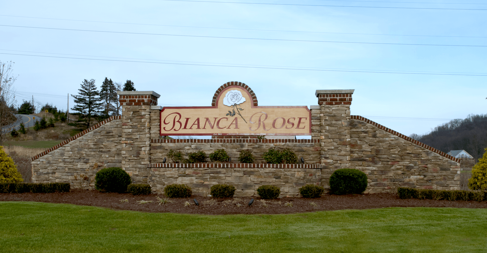 A stone wall with a sign that says bianca rose