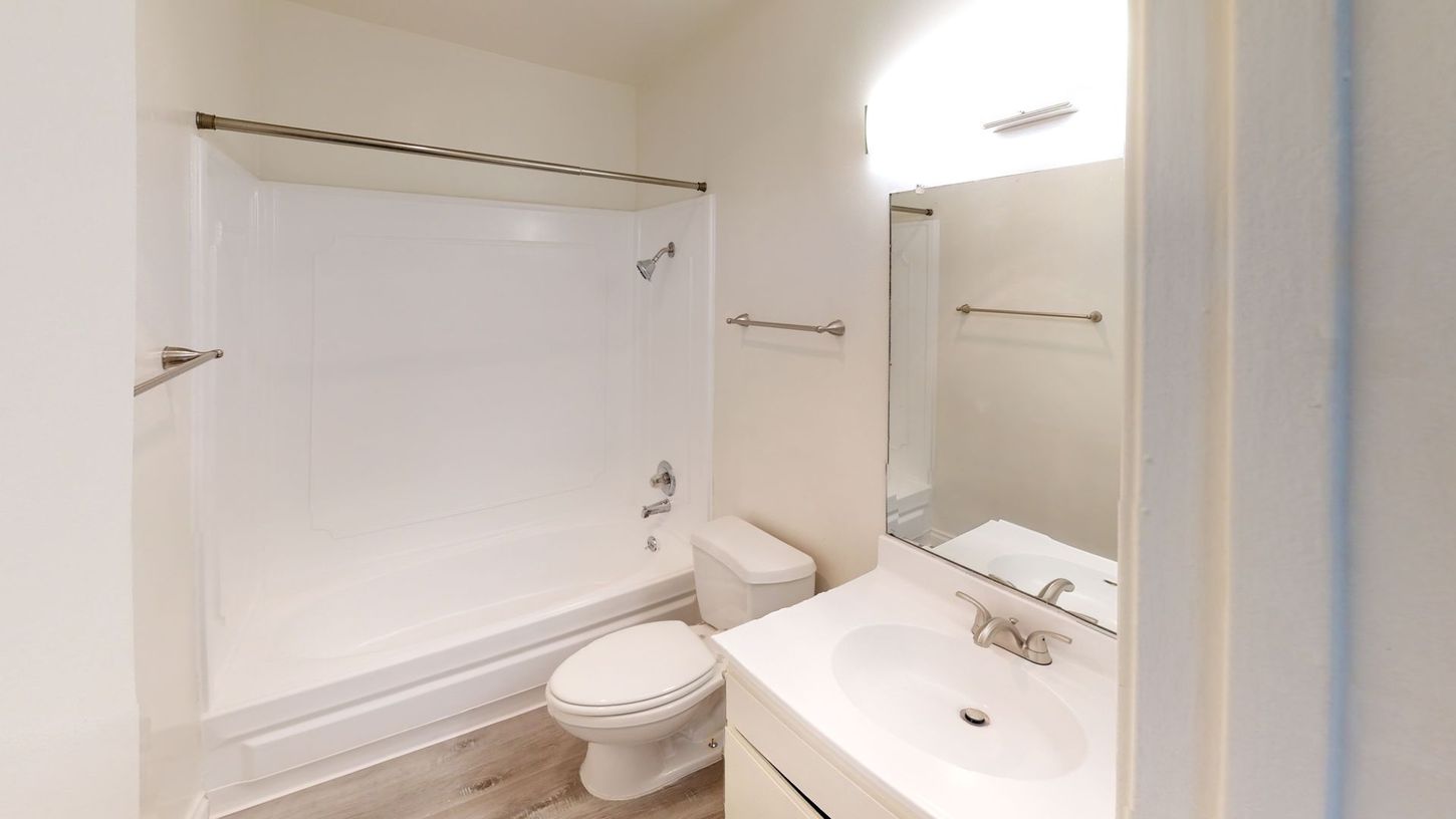 Bright white bathroom with a tub/shower, toilet, and vanity.