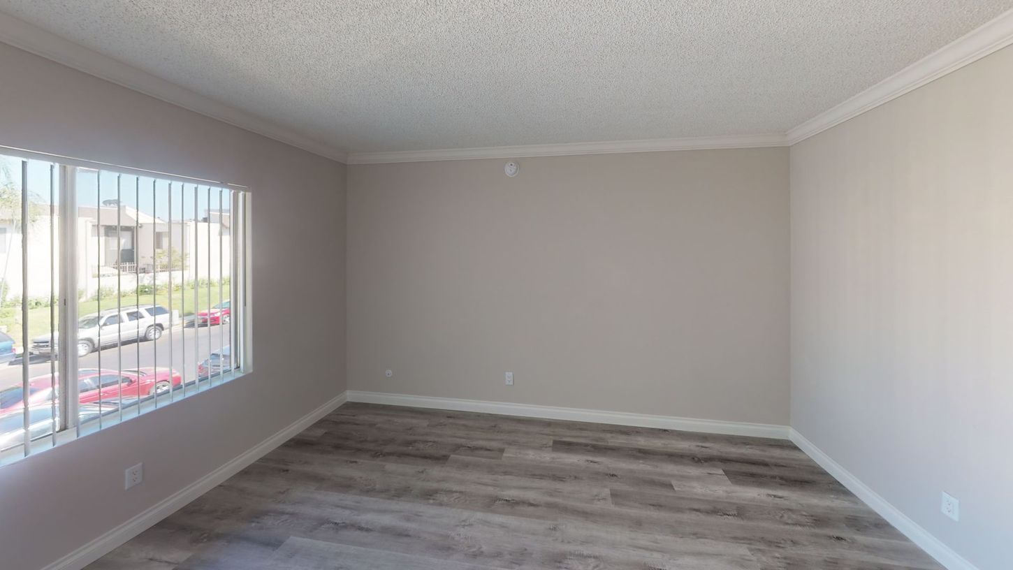 Empty room with gray walls, wood-look flooring, and a window with blinds.