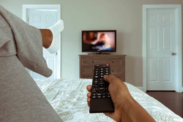 A person is holding a remote control in front of a television.