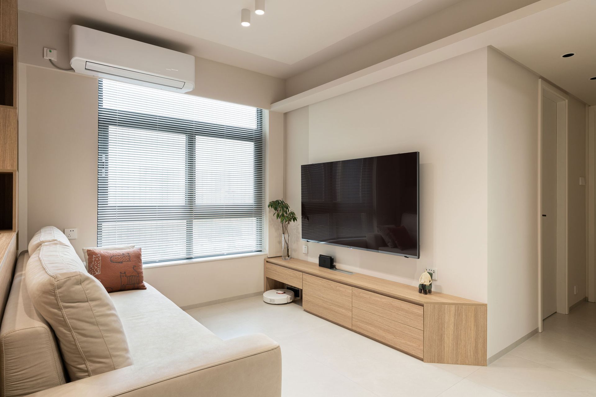 A living room with a couch , television , and window.