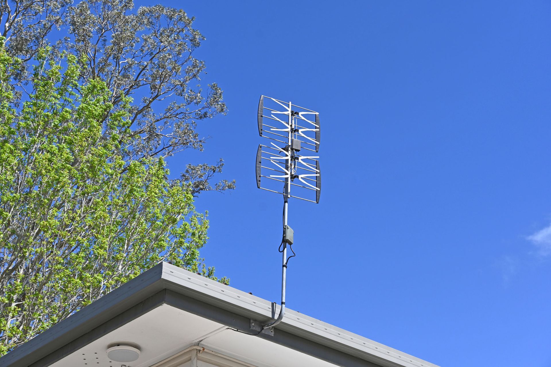 An antenna on top of a building with a tree in the background